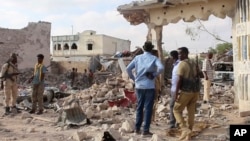 ታዛቢዎች እና የፀጥታ መኮንኖች በማዕከላዊ የሶማሌ ከተማ ቤለድዌን ከተማ በሚገኝ ሆቴል በመኪና ላይ የተጠመደ ቦምብ ፍንዳታ ያስከተለውን ሁኔታ ይመለከታሉ፤ እአአ መጋቢት 12/2025