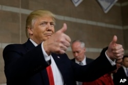 Republican presidential candidate Donald Trump gives thumbs up as he visits a caucus site, Feb. 23, 2016.
