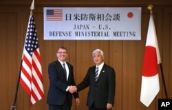 U.S. Defense Secretary Ash Carter, left, and Japan's Defense Minister Gen Nakatani shake hands prior to a meeting at the Defense Ministry in Tokyo, Wednesday, April 8, 2015.