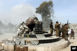 Turkey-backed Free Syrian Army soldiers celebrate around a statue of Kawa, a mythology figure in Kurdish culture, after destroying it in the city center of Afrin, northwestern Syria, March 18, 2018.