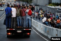 People ride in a truck and walk on a street during a blackout in Caracas, Venezuela, Feb. 6, 2018.