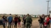 Familias inmigrantes solicitantes de asilo esperan ser transportadas por la Patrulla Fronteriza de EE. UU. en La Joya, Texas, después de cruzar el Río Grande desde México en abril de 2021.