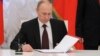 Russian President Vladimir Putin prepares to sign a law on ratification of a treaty making Crimea part of Russia, during a ceremony in Moscow's Kremlin in Moscow, March 21, 2014. 