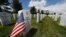 A flag stands next to the gravestone for a U.S. World War II veteran, at Fort Logan National Cemetery, in Sheridan, Colorado, May 23, 2020. 