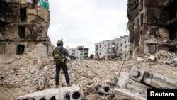 Seseorang berdiri di depan bangunan yang hancur saat serangan Rusia ke Ukraina berlanjut, di wilayah Kyiv, Ukraina, 13 April 2022. (Foto: via Reuters)