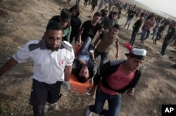Palestinian protesters evacuate a wounded man during a protest at the Gaza Strip's border with Israel, April 13, 2018.