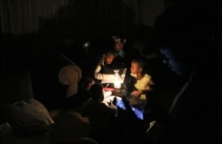 FILE - Children use a parafin light to study during an electricity load-shedding blackout in Soweto, South Africa, March 18, 2021.