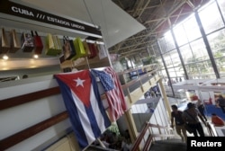FILE - U.S. and Cuban flags hang on a wall at the U.S pavilion during the Havana International Fair, Havana, Cuba, Nov. 2, 2015.
