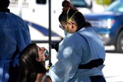 Cindy Tahuico (der)hace una prueba de COVID-19 a Daniela DeMicuel (izq), en un punto móvil de pruebas en Miami Beach, Florida, el sábado 12 de diciembre de 2020.