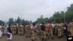 Ethiopian soldiers block the street as people march during an annual religious festival in Bishoftu, a town southeast of Ethiopia's capital, Addis Ababa, Sunday, Oct. 2, 2016.