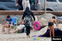 Seorang perempuan Muslim mengenakan burkini, pakaian renang yang hanya memperlihatkan wajah, tangan dan kaki, di sebuah pantai di Marseille, Prancis, 17 Agustus 2016. (Foto: Reuters)