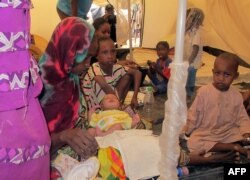 FILE - A family of refugees from Central Africa sit under a tent with their new baby.