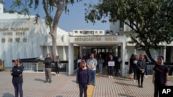 FILE - Hong Kong public broadcaster RTHK staffers wear masks resembling journalist Nabela Qoser during a silent protest against the management's treatment of Qoser, known for her tough questioning of officials, outside Broadcasting House, Jan. 28, 2021.