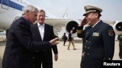 U.S. Secretary of Defense Chuck Hagel (L) is welcomed by Rear Admiral Guan Youfei, Director of Foreign Affairs Office of the Chinese Defense Ministry and U.S. Ambassador to China, Max Baucus (2nd L), upon his arrival at Qingdao International Airport, Apri