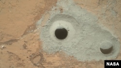 At the center of this image from NASA's Curiosity rover is the hole in a rock called "John Klein" where the rover conducted its first sample drilling on Mars. 