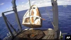 In this image from video made available by NASA, the SpaceX Crew Dragon capsule is hoisted onto a ship in the Atlantic Ocean off the Florida coast after it returned from a mission to the International Space Station. (NASA via AP)