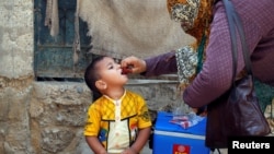 A boy receives polio vaccine drops, during an anti-polio campaign, in a low-income neighborhood in Karachi, Pakistan, April 9, 2018. 