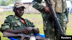 FILE - M23 rebels hold their weapons as they keep watch near a United Nations peacekeepers check point at Kanyaruchinya village, 3km (1.9 miles) north of Goma city May 15, 2013.