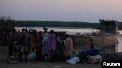 People displaced by the fighting in Bor county, stand by their belongings after arriving in the port of Minkaman, in Awerial county, Lakes state, in South Sudan, Jan. 14, 2014. 