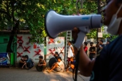 Anti-coup protesters and residents monitor police and military occupying a roadblock in Yangon, Myanmar, March 19, 2021.