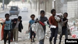 Children walk as they collect empty plastic bottles in a street in Sanaa, Yemen, Nov. 21, 2019. 