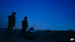 FILE - Russia-backed rebels are seen guarding territory after sunset near Donetsk, eastern Ukraine, Aug. 2, 2015.