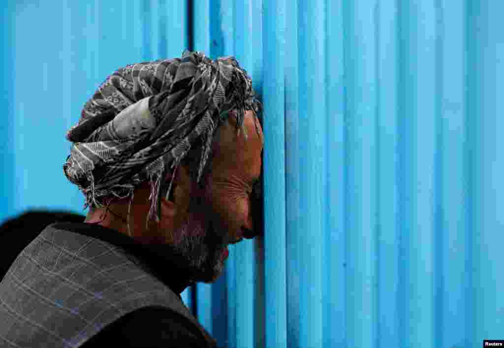 Seorang pria Afghanistan meratap di pintu gerbang masjid Sakhi setelah serangan bunuh diri di Kabul, Afghanistan.