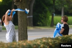 Denise Koesterman and Alison Lebrun, right, both of Cincinnati, hang ribbons in honor of Otto Warmbier's homecoming in the Wyoming neighborhood of Cincinnati, Ohio, June 13, 2017.