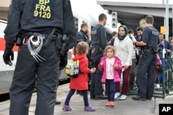 FILE - Refugees wait for a train at the rail station in Freilassing, southern Germany, near the Austrian border, Sept. 18, 2015.
