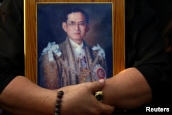 A mourner holds a portrait of Thailand's late King Bhumibol Adulyadej in Bangkok, Thailand, Oct. 14, 2016.