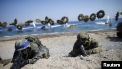 South Korean (blue headbands) and U.S. Marines take positions as amphibious assault vehicles of the South Korean Marine Corps fire smoke bombs during a U.S.-South Korea joint landing operation drill in Pohang, South Korea, March 12, 2016. 