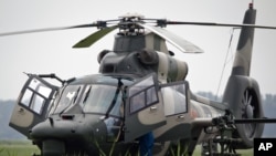 Flight crew of a Z-9WZ attack helicopter, designed and manufactured by China, chat after a flight demonstration for press at a Chinese Liberation Army base, ahead of Army Day on Aug. 1, on the outskirts of Beijing, China Tuesday, July 24, 2012.