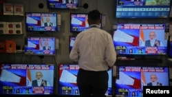 A salesman watches Prime Minister Narendra Modi addressing to the nation, on TV screens inside a showroom in Mumbai, India, March 27, 2019. 