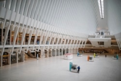 A pedestrian stands along in a sparsely populated transit hub in the downtown financial district as retail stores remain shuttered due to COVID-19 concerns, Saturday, March 21, 2020, in New York. New York Gov. Andrew Cuomo announced sweeping orders.