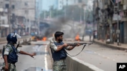 গত বছর সরকার-বিরোধী আন্দোলনের শেষ পর্যায়ে ঢাকায় একজন পুলিশ সদস্যকে বিক্ষোভকারীদের লক্ষ্য করে তার রাইফেল তাক করতে দেখা যাচ্ছে। ফাইল ফটোঃ ৫ অগাস্ট, ২০২৪।