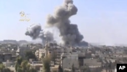 This image taken from video obtained from the Ugarit news network, which has been authenticated based on its contents and other AP reporting, shows smoke rising from the city following heavy bombing from military warplanes, in Deir el-Zour's Jbeileh neigh