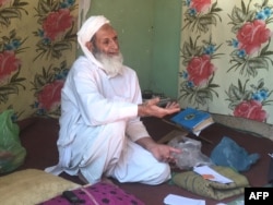 FILE - An Afghan refugee talks to EU officials and aid workers who visited his home in Kerman, Iran, Oct. 23, 2016.