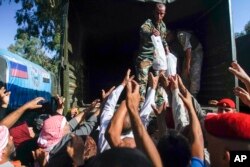 Soldiers distribute Russian humanitarian aid at the check-point of the de-escalation zones near Homs, Syria, Wednesday, Sept. 13, 2017.