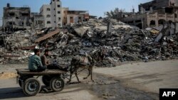 উত্তর গাজার বেইট লাহিয়াতে ইসরাইলি হামলায় ধ্বংস হওয়া ভবনগুলির পাশ দিয়ে গাধা-টানা গাড়ি যাচ্ছে ৷( ২৬ ফেব্রুয়ারী, ২০২৪)