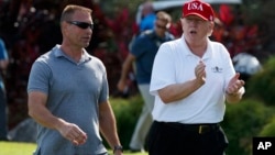 FILE - President Donald Trump walks with Gene Gibson, commanding officer at Coast Guard Station Lake Worth Inlet, as he arrives, Dec. 29, 2017, to meet with members of the U.S. Coast Guard, who he invited to play golf, at Trump International Golf Club, in West Palm Beach, Fla. 