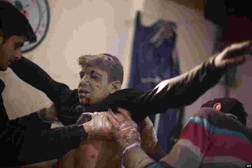 Medics treat an injured Syrian boy at a makeshift hospital in the rebel-held Damascus suburb of Douma, following two reported air strikes by government forces, Dec. 8, 2014.