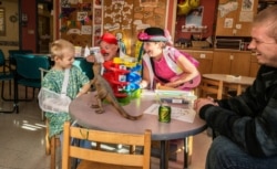 Jay Stewart (in red hat), in clown character as bumbling handyman Doc Skeeter, visits a young patient at Boston Children’s Hospital. (Photo courtesy Dr. George Taylor)