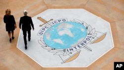 FILE - People walk past the Interpol logo at the headquarters of the international police agency in Lyon, France, Nov.8, 2018. 