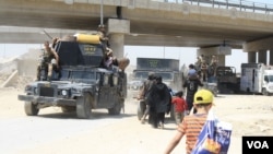 Families take shelter under a bridge where they meet trucks and buses transporting civilians to camps while soldiers travel the opposite direction to the front lines in Mosul, Iraq, June 4, 2017. (H. Murdock/VOA)