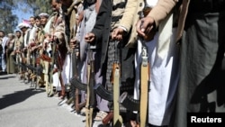 FILE - Houthi supporters hold their wehiapons during a demonstration outside the U.S. Embassy against the United States over its decision to designate the Houthis a foreign terrorist organization, in Sana'a, Yemen, Jan. 18, 2021. 