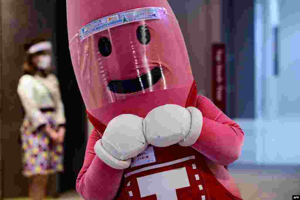 A person dressed as the mascot of Tokyo Tower wears a face shield while waiting to greet patrons at the entrance of the 332.9 meter (1,092 foot) high tower, as the city's landmark reopened following coronavirus lockdown.