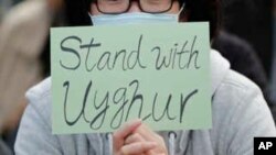 FILE - A man holds a sign during a rally to show support for Uighurs and their fight for human rights in Hong Kong, December 22, 2019. 
