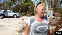 Dixie Crystal Mathews wipes away tears as the American flag is raised above the sea. “We are going to get through this,” she said. “Now we know it’s going to be okay.” (R. Taylor/VOA)