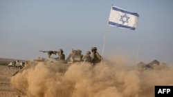 FILE - Israeli soldiers on an armoured personnel carrier flying an Israeli flag return from the Gaza Strip near Israel's border, July 23, 2014.