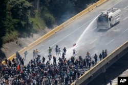 FILE - Security forces spray a water canon at opposition protesters marching to protest Venezuelan President Nicolas Maduro in Caracas, Venezuela, May 29, 2017.